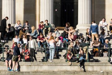 Crowd of University College London (UCL) students relaxing in sunshine