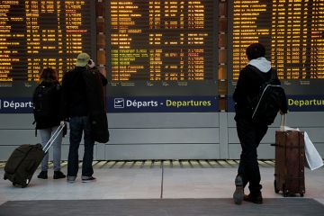 Passengers check departures board