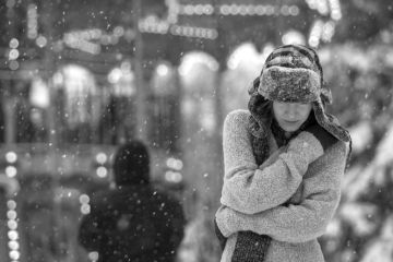 A depressed woman walks in the snow