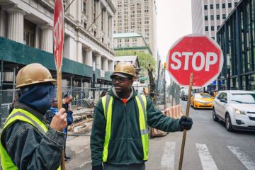 A minority ethnic man with a sign to stop traffic A minority ethnic man with a sign to stop traffic