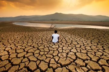 A boy sits on the cracked bed of a drying lake A boy sits on the cracked bed of a drying lake