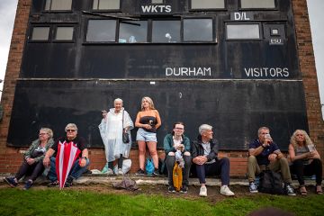 People sit next to a cricket scoreboard as they attend the Durham Miners Gala in Durham, England. To illustrate that elite universities face a ‘balancing act’ over local students.