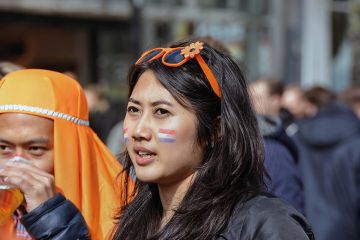 A young Asian woman has the Dutch flag painted on her cheek