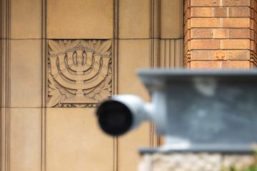 A Menorah engraved in sandstone on the Emanuel Synagogue on Ocean Street, Woollahra in the eastern suburbs of Sydney. In the foreground is a security camer