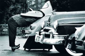 man looks under car bonnet