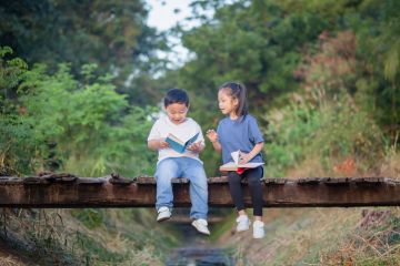 Two children read books on a bridge Two children read books on a bridge, symbolising humanities students becoming engineers