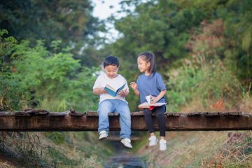 Two children read books on a bridge, symbolising humanities students becoming engineers