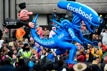 A carnival float depicting a judge holding the tail of an alien whereupon is written 'radicalisation, hate, rush, Facebook' is pictured during the Rose Monday carnival street parade in Duesseldorf, western Germany on February 24, 2020 A carnival float depicting a judge holding the tail of an alien whereupon is written 'radicalisation, hate, rush, Facebook' in Germany 2020. To illustrate whether scholars on Facebook's oversight board are helping rule on moderation rows.