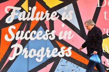 A man walks past artwork saying 'failure is success in progress' in Stoke-on-Trent, England. To illustrate low outcomes for business courses. A man walks past artwork saying 'failure is success in progress' in Stoke-on-Trent, England. To illustrate low outcomes for business courses.
