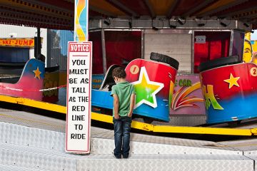 Fairground waltzers ride with minimum height safety notice and disappointed child. To illustrate minimum entry standards. Fairground waltzers ride with minimum height safety notice and disappointed child. To illustrate minimum entry standards.