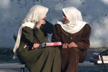 Female students chatting on bench Female students chatting on bench