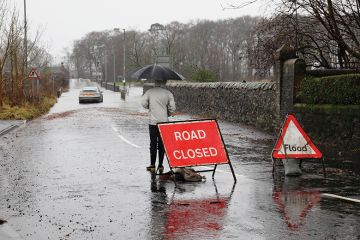 A sign before a flooded road says 'Road closed'