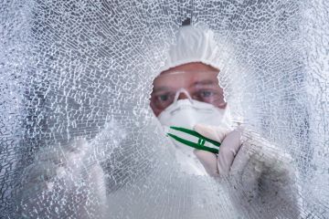 Forensic examiner inspecting broken shatterproof window