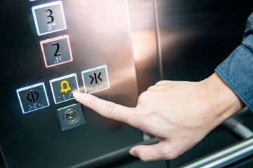 Forefinger pressing on emergency stop and alarm button in elevator Forefinger pressing on emergency stop and alarm button in elevator