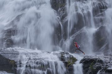 climber jumping between rocks under the "Cascata del Toce" (Toce waterfall), a waterfall in the Italian Alps climber jumping between rocks under the "Cascata del Toce" (Toce waterfall), a waterfall in the Italian Alps