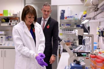 Britain's Chancellor of the Exchequer Rachel Reeves puts on gloves, as she and Britain's Secretary of State for Science, Innovation and Technology Peter Kyle visit the Cambridge Biomedical Campus