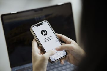 A person holding a smartphone displaying a conversation with an AI tool which says "Hi, may I help you?"