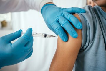 Doctor administering vaccine to teenager in doctor's office Doctor administering vaccine to teenager in doctor's office