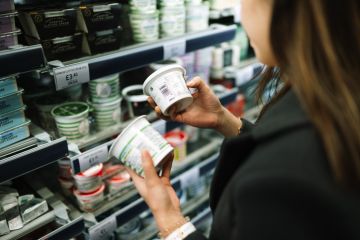 A woman in a grocery store comparing the labels on the back of two containers