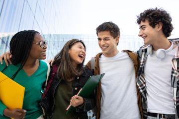 Group of cheerful students walking and laughing together outside Group of cheerful students walking and laughing together outside