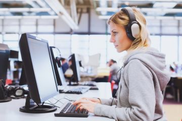 Student in headphones working on computer in library