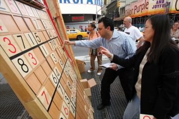 Jim Ressler, owner of Sudoku Board USA, helps Dorris Lam of Glen Rock, N.J., solve a Sudoku puzzle on a gigantic board in Times Square