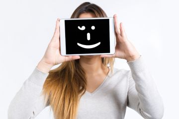 Girl holding a tablet computer with a smiley face on it