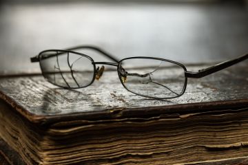 Cracked glasses on an old book, symbolising poor presidential searches