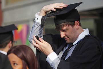 Students adjust their caps ahead of their graduation ceremony, London, UK. To illustrate that over half of graduates regret their undergraduate decisions 
