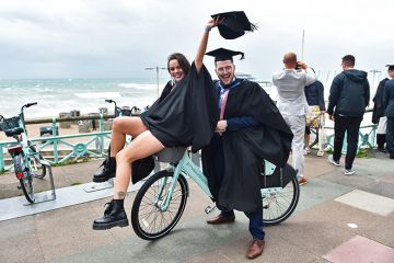 Students celebrate their success on graduating from the University of Brighton on a windy seafront after the ceremony. As an illustration that the public perception of 'graduate regret' is overestimated.