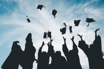 Graduates throw their caps into the air, symbolising the graduate premium Graduates throw their caps into the air, symbolising the graduate premium