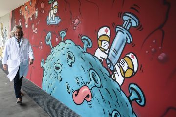 French microbiologist Didier Raoult walking past a wall of Covid graffiti French microbiologist Didier Raoult walking past a wall of Covid graffiti