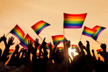Group of people waving Gay Pride symbol flags