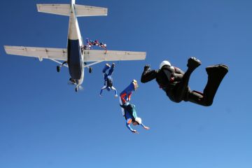 Group of parachutists jump together from an airplane against the blue sky