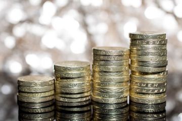 Growing piles of British pound coins Growing piles of British pound coins
