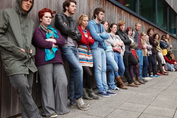 Crowd of grumpy looking students leaning against a wall, to illustrate a rise in student complaints. Crowd of grumpy looking students leaning against a wall, to illustrate a rise in student complaints.