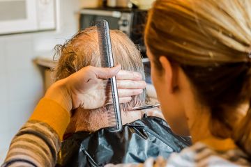 woman give elderly man haircut woman give elderly man haircut