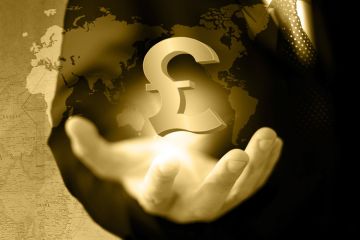 Hand holding UK pound currency symbol against world map Hand holding UK pound currency symbol against world map