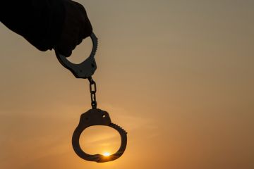 A person holding up handcuffs in the sunrise, symbolising autonomy A person holding up handcuffs in the sunrise, symbolising autonomy