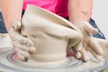 Hands working clay on potter's wheel