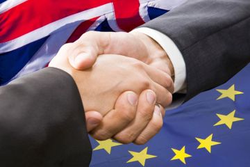 Handshake in front of European Union and United Kingdom flags Handshake in front of European Union and United Kingdom flags