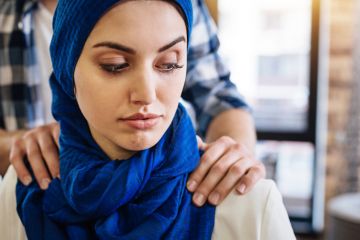 A Muslim woman with male hands on her shoulders, signifying sexual harassment in the Middle East