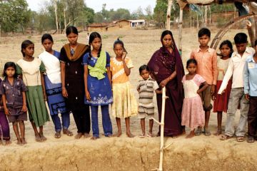 Indian women and children standing beside well