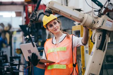 An industry robot is adjusted by an engineer illustrating an op-ed about industry-university collaboration