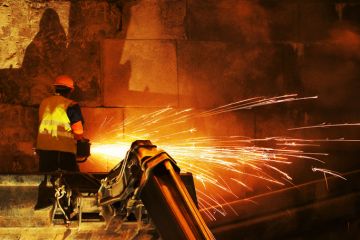 Industry worker welding steel and stone structure of building wall