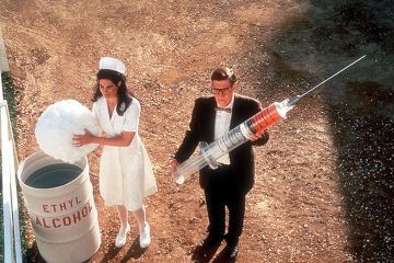 Nurse and man holding giant syringe Nurse and man holding giant syringe