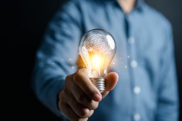 A man offers a lit lightbulb, signifying innovation