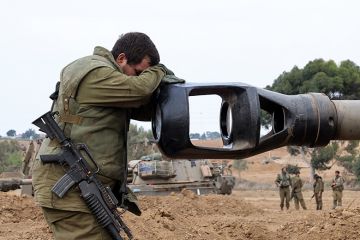 An Israeli soldier rests his head on the gun barrel of a self-propelled artillery howitzer as Israeli soldiers take positions near the border with Gaza in southern Israel on October 9, 2023 An Israeli soldier rests his head on the gun barrel of a self-propelled artillery howitzer as Israeli soldiers take positions near the border with Gaza in southern Israel on October 9, 2023