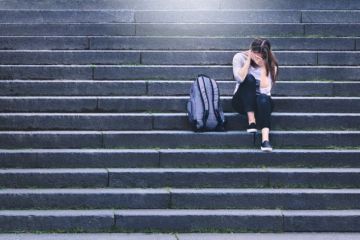 An upset woman sits alone on some steps