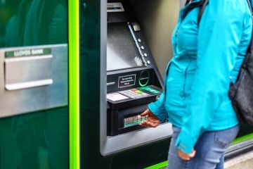 Young adult woman withdrew from cash machine.